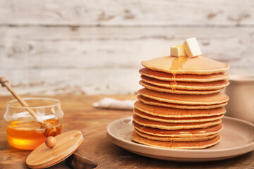 Tasty pancakes with butter and honey on table