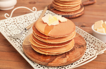 Tasty pancakes with butter and honey on table