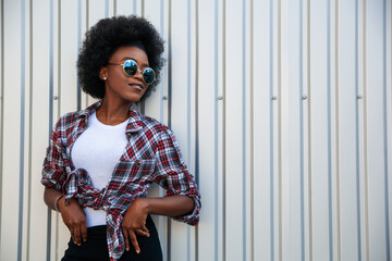 People concept — african american young female wearing sunglasses with curly hair over grey background, copy space. Lifestyle.