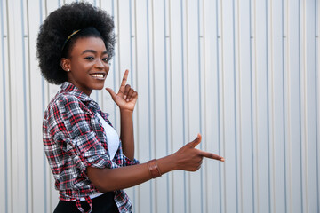 Promotion concept. Cheerful african american girl pointing aside on free space, recommending something. Grey background..