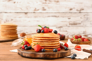 Sweet pancakes with berries on table