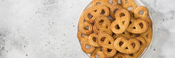 Liver with sugar in a white plate on a light gray table. Pretzel cookies sprinkled with sugar. Banner with space for text