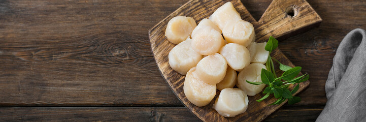 Scallops on a wooden Board on a brown wooden table. Scallops close-up. Top view with space for...