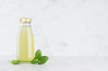 Fresh vegetable green spinach juice in glass bottle template with leaves on wood table and white background with copy space.