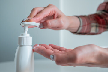 Disinfection, protection, prevention, COVID-19, coronavirus, safety, sanitation concept. Woman pushing dispenser, squeezing out antiseptic gel on palm, cleaning hands - close up side view