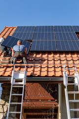 Workers installing solar electric panels on a house roof in  Ochojno. Poland