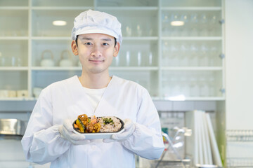 お弁当を持つ男性調理師　宅食　デリバリー　テイクアウト