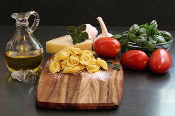 Tortelli on a cutting board with ingredients to make dinner.