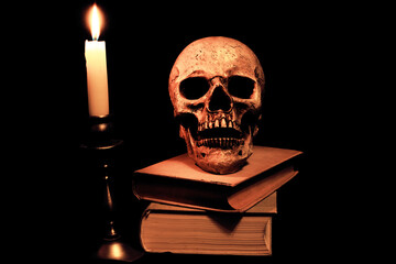 Bücher und ein Schädel im Licht einer Kerze