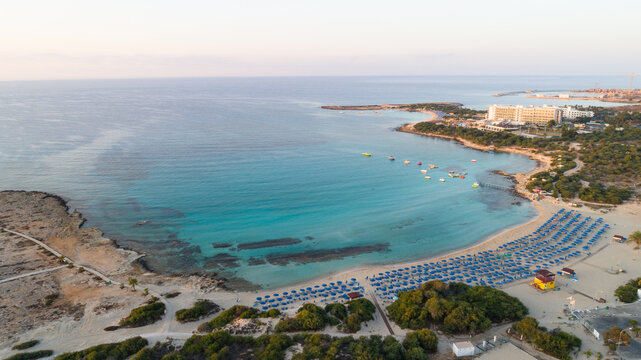 Aerial bird's eye view of Landa beach, Ayia Napa, Famagusta, Cyprus. Landmark tourist attraction golden sand bay at sunrise with boats anchored between Makronissos and nissi in Agia Napa, from above. 