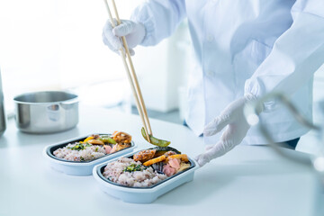 弁当を盛り付ける男性調理師　宅食　デリバリー　テイクアウト