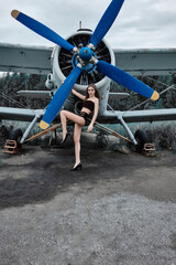 young beautiful girl in a black swimsuit stands at the propeller of the plane in a headset