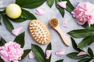 Concept SPA and Wellness. Massage brush, cosmetic oils and soap. Light background with peony flowers.
