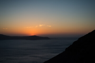 Sunset over the sea and the south end of the island of Santorini, Greece. View from Fira, the capital