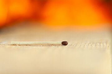 Match on a wooden surface on a background of flame.