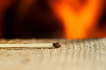 Match on a wooden surface on a background of flame.