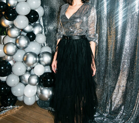 women in shiny silver dresses at a party decorated with balloons. celebration with dress code