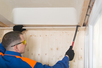 disassembly of the room by a master in a blue uniform, dismantling, opening the wooden ceiling...