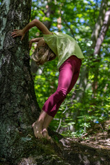 Mädchen beim unbeschwerten Sport und turnerischer Bewegen, wie Akrobatik in der Freizeit, im Wald und in der Natur. Sie trägt legere Kleidung, Shirt und Leggins.