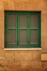 Closed window with wooden green shutters in the house. Close-up.