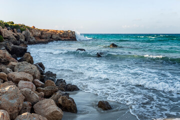 A seething blue sea with foamy waves on a rocky shore. Wild beach, beautiful nature. Background. Space for text.