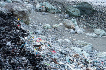 Lot of reusable plastic trash and household items rubbish washed up by the sea, on stony beach on Noto Peninsula, Japan. 