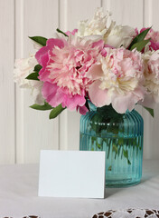 bouquet of peonies and a white card, space for text.