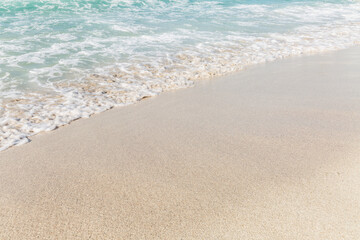 Turquoise sea with foamy waves on a sandy beach. Tourism and travel. Space for text.