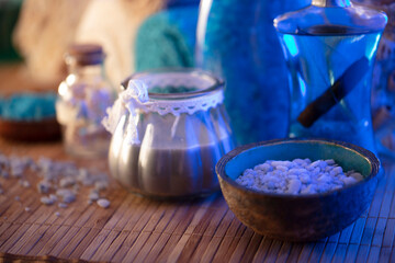 Spa and wellness concept. Bottles with cosmetics, rolled up towels, bath salts and care products on wooden paneling.