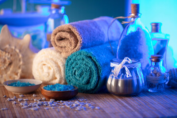 Plakat Spa and wellness concept. Bottles with cosmetics, rolled up towels, bath salts and care products on wooden paneling.