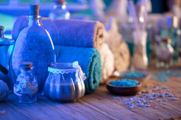 Spa and wellness concept. Bottles with cosmetics, rolled up towels, bath salts and care products on...