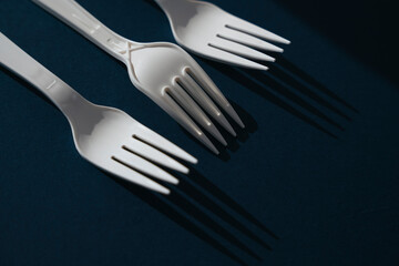 Three white plastic utensil fork laying together.