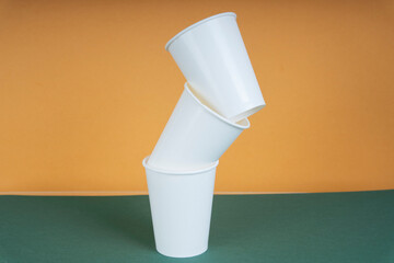 Stack of disposable plastic paper cup on green table.
