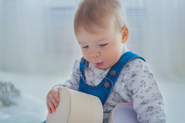 Little boy playing with empty gift box in bright white room at home - close up view. Christmas, New Year, family, childhood, leisure time, holiday concept