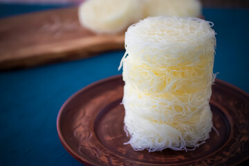 Dry funchose on brown board and plate on blue cement background.