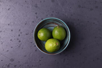 exotic tropical green citruses (limes) on the dark grey concrete stone surface. space for text. minimalism style. top view