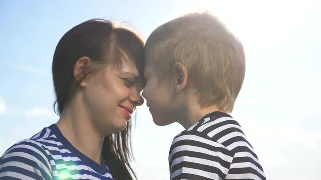 A beautiful happy family. Mother and son touch their noses. Family in the sunshine enjoy the positive emotions of reunion and a good life. Happy childhood and motherhood.