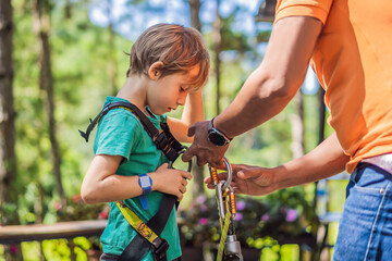 Instructor puts on the child climbing equipment for safe passage on the rope park