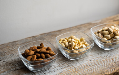 Almond, pistachio and cashew in a small plates which standing on a vintage white table. Nuts is a healthy vegetarian protein and nutritious food.