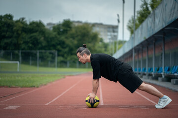Fototapeta premium muscular young athlete has workout and exercising with medicine ball outdoor