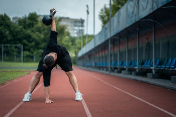 young athlete has workout and doing sport exercises with kettlebell outdoor