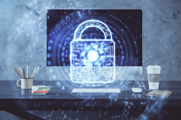Double exposure of desktop with computer and lock icon hologram. Concept of data safety.