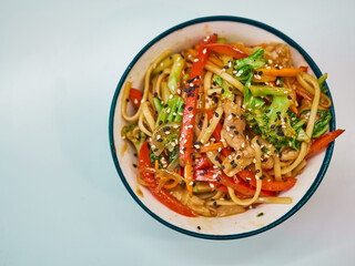 Udon noodles with meat in a plate on a white surface. With vegetables greens