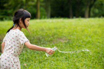 真夏の公園でガラス瓶で水遊びをしている可愛い子供