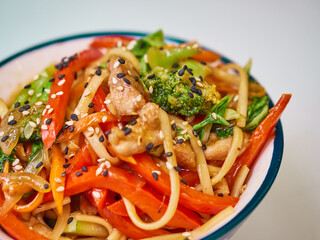 Udon noodles with meat in a plate on a white surface. With vegetables greens