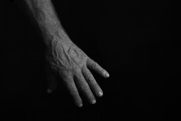 A man's, manly hand against a black background. The photo is in a low key. Horizontal.
