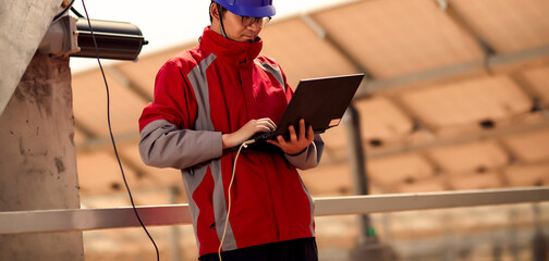 Asian engineers use laptops to adjust automatic rotating bearings in outdoor solar photovoltaic areas