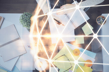 Social network theme hologram over hands taking notes background. Concept of global international people connect. Double exposure