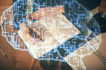 Double exposure of writing hand on background with brain hologram. Concept of learning.