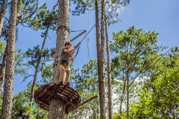 Fototapeta premium Young attractive man in adventure rope park in safety equipment